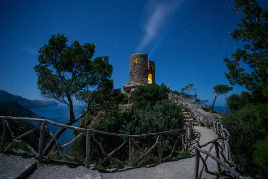 Lights from tower on top of high hill near sea and wonderful sky in evening