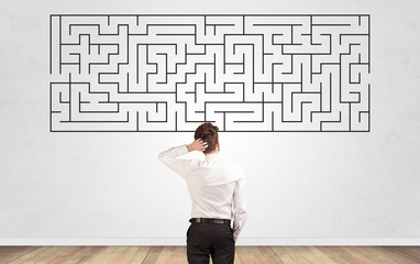 Businessman in doubt looking to a maze and searching the way out