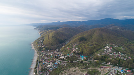 Fototapeta premium Beautiful aerial view of a coastal settlement at evening. Golovinka, Sochi. view of the highest bridge in Russia. serpentine in the mountains 