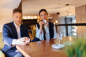 A stylish couple drinks morning coffee at the cafe, young businessmen and freelancers