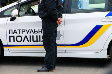 A policeman stands near a patrol police car with the inscription in Ukrainian "Patrol Police", Dnepropetrovsk, Dnipro city, Ukraine