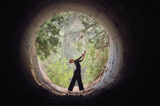 Woman dancing ballet in pipe tunnel