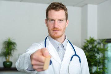 portrait of doctor holding wooden spatula forwards