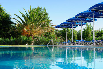 Palm and sun umbrellas by the pool, Greece.
