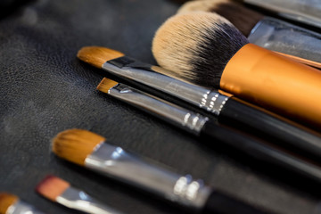 Set of makeup brushes lying on darn surface close