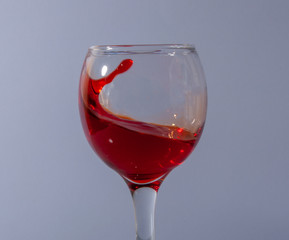 red wine splash in glass on white background