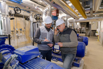 two workers in blue uniform in industrial hall
