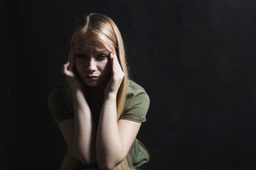 Sad young woman going to cry in a black background