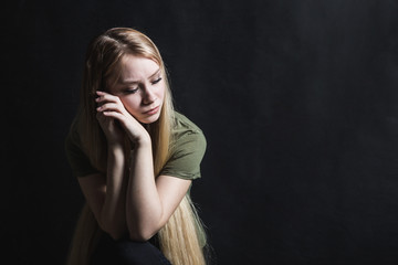 Sad young woman going to cry in a black background