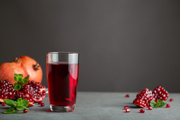 Pomegranate juice in a glass on gray background.