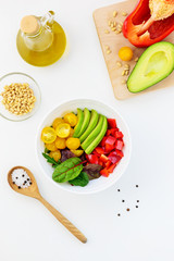 Fresh vegetable salad on the white table. Sliced tomatoes, avocado and pepper with greens.