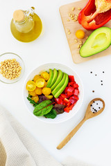 Fresh vegetable salad on the white table. Sliced tomatoes, avocado and pepper with greens.