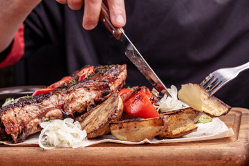 Delicious barbecued ribs seasoned with fresh herbs, cabbage salad, backed potato on an old rustic wooden chopping board