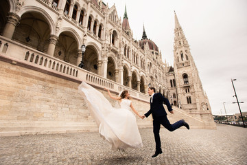 Bride and groom hugging in the old town street. Wedding couple walks in Budapest near Parliament...