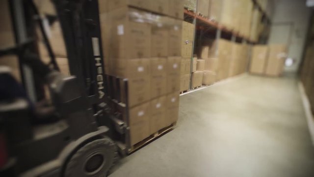 Medium shot of warehouse worker driving forklift truck in warehouse