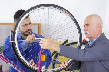 two bicycle repairer colleagues working in bike garage