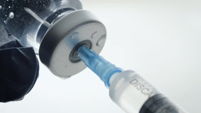 Extreme closeup of filling a syringe from a vaccine bottle. Mandatory vaccinations are currently a hotly debated topic with anti-vaxxers. Causing global outbreaks of preventable diseases like measles.
