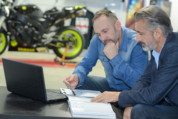 worker and customer examine motobike damage