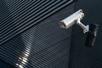 Modern CCTV camera on a wall. A blurred night cityscape background. Concept of surveillance and...