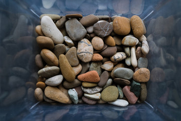 Stones of many types and sizes. Close-up view of pebbles in the box. Top view, marine concept.
