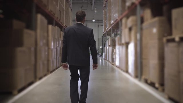 Medium shot of rear view businessman walking in warehouse