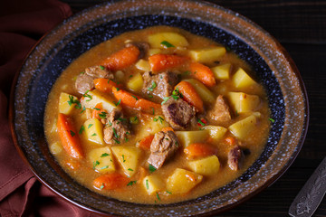 Homemade beef stew with vegetables in bowl on wooden table