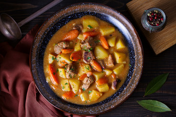 Homemade beef stew with vegetables in bowl on wooden table