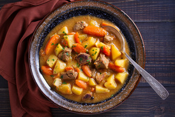 Homemade beef stew with vegetables in bowl on wooden table