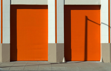 Orange doors and garage with masonery frame and wall sidewalk