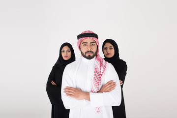 Two arab females with one male smiling and standing on white background