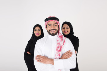 Two arab females with one male smiling and standing on white background