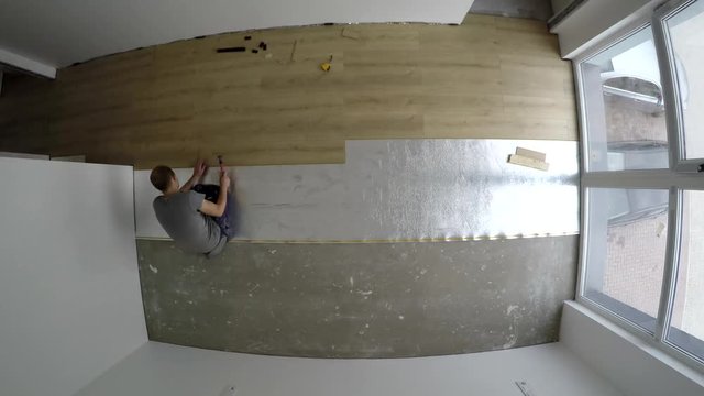 Men joining laminate board floor in new apartment room