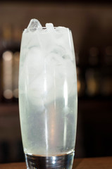 close up of alcohol drink with ice and on wooden table in bar