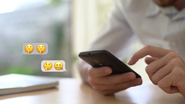 Close-up shot of young man using an emojis while chatting on smartphone