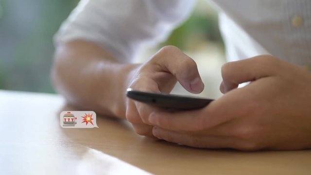 Close-up shot of young man using an emojis while chatting on smartphone
