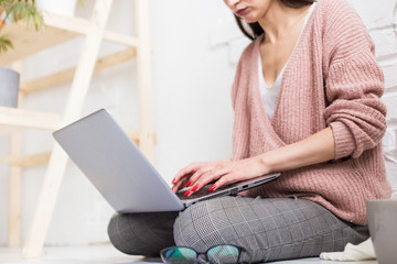 Young woman sits on the floor in a Scandinavian apartment interior with a laptop, studying law, freelance girl at work, distance learning student, online employment, paperwork and outsourcing concept