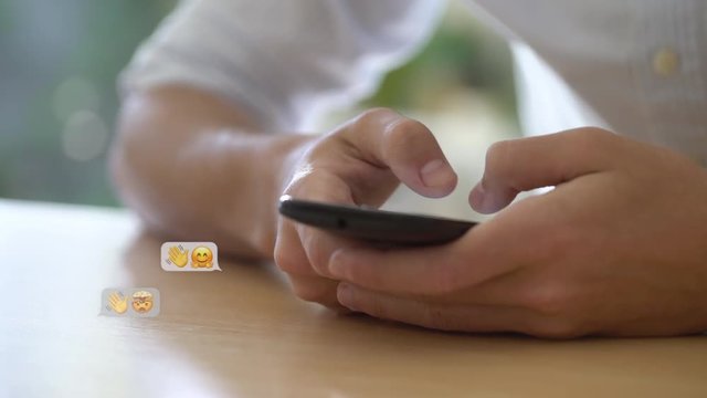 Close-up shot of young man using an emojis while chatting on smartphone