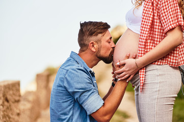 Fototapeta premium Young man kissing his pregnant wife's belly