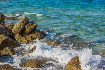 waves breaking on stone local Mediterranean sea coastline in Greece scenic landscape in summer bright colorful lighting 