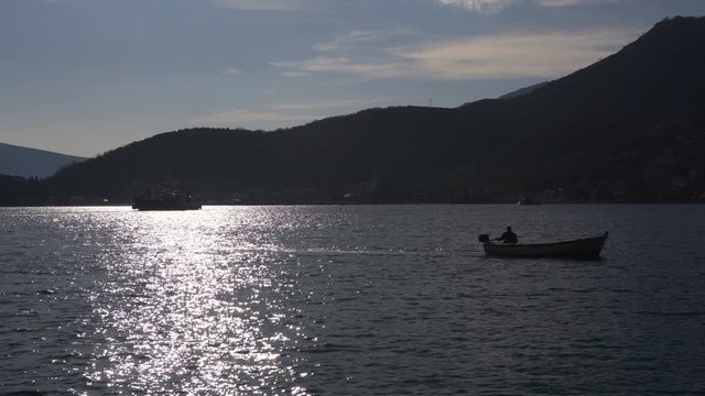 Fisherman silhouette on boat catching fish in river on background evening sunset