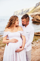 Portrait of a young pregnant woman posing with her husband on a sunny summer day
