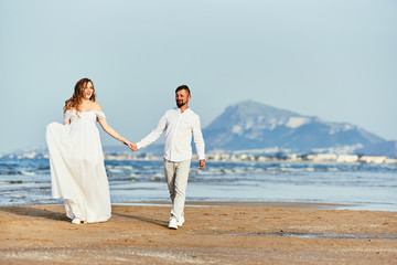 Fototapeta premium Young pregnant woman walking with her husband on the beach