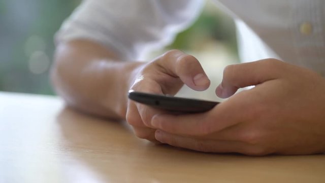 Close-up shot of young man texting on smart phone at home