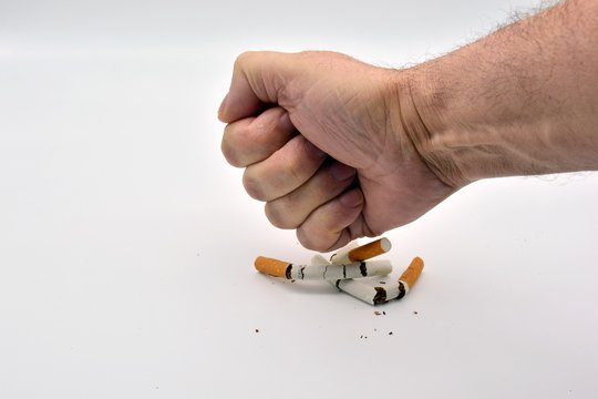 Mano dando pu&ntilde;etazo al tabaco, rompiendo cigarrillos
