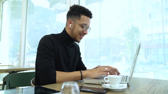 Medium shot of a businessman using laptop while listening music in a restaurant
