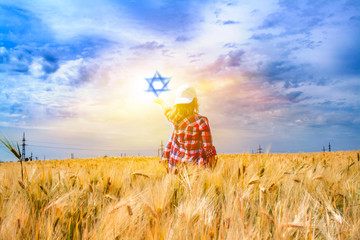 Child's hand holding  star of David . David star on blue sky . 