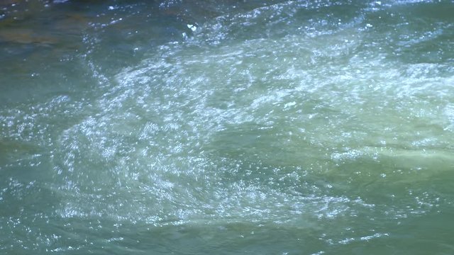 The current from a clean, clear turquoise creek rotates into an eddy creating a beautiful flowing current as it spills from an untouched Ozark Mountain creek. 