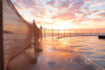 Sunrise at Bronte Beach Pool, New South Wales, Australia. Waves on the rocks. - obrazy, fototapety, plakaty