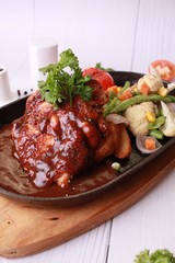 Grilled chicken with sauce on stone plate. 