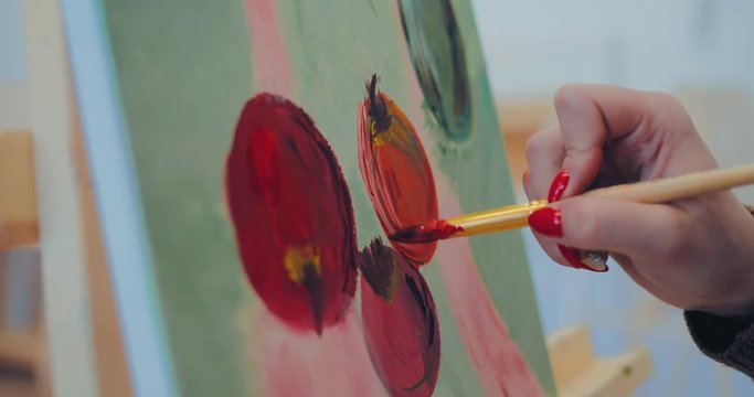 Artist paints to paint apples on canvas. Close-up.